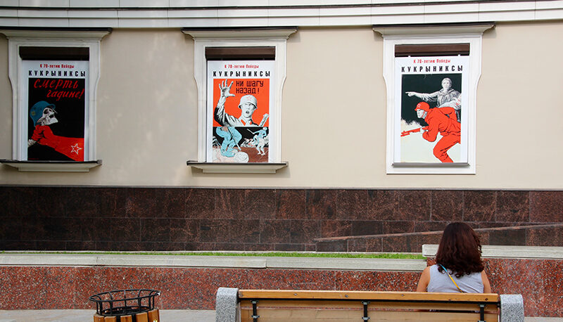 A collection of anti-Nazi posters from the USSR. The first poster reads, "death to the bastards" in Russian with a red arm holding a skull wearing a Nazi helmet. The second poster says "not one step back" in Russian, with a USSR soldier exclaiming above a picture of Nazis pillaging a village. The third poster depicts a USSR solider charging forward at the orders of a mother with a child in her arms.