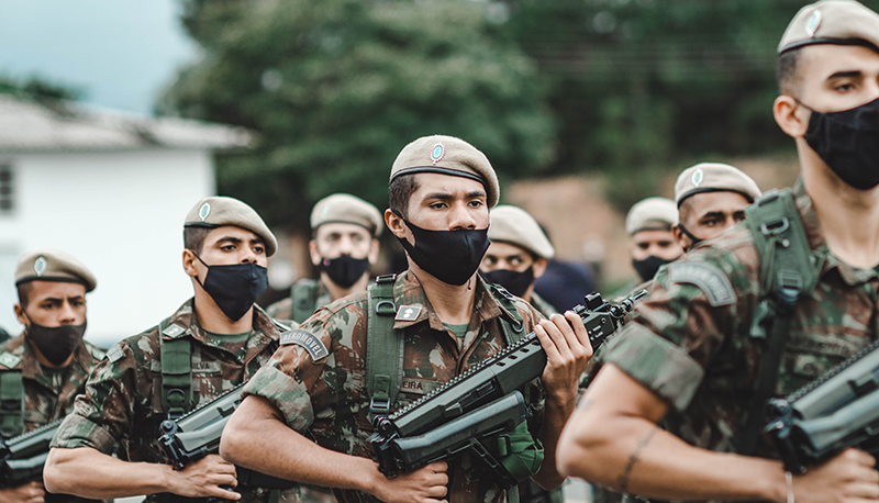 Iranian soldiers marching with firearms. They are wearing camouflage and berets.