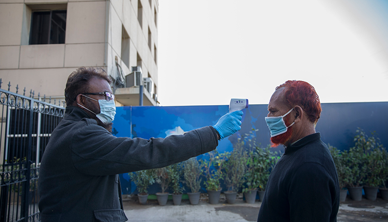 A man checks temperature of everyone who enters the Pakistan Stock Exchange building.