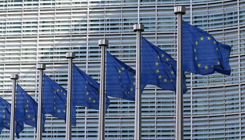 Line of seven blue European Union flags flying outside of the European Commission Berlaymont in Brussels