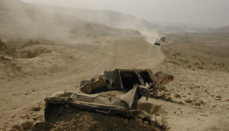 Remnants of a damaged vehicle lie next to a dry dirt road in Kabul