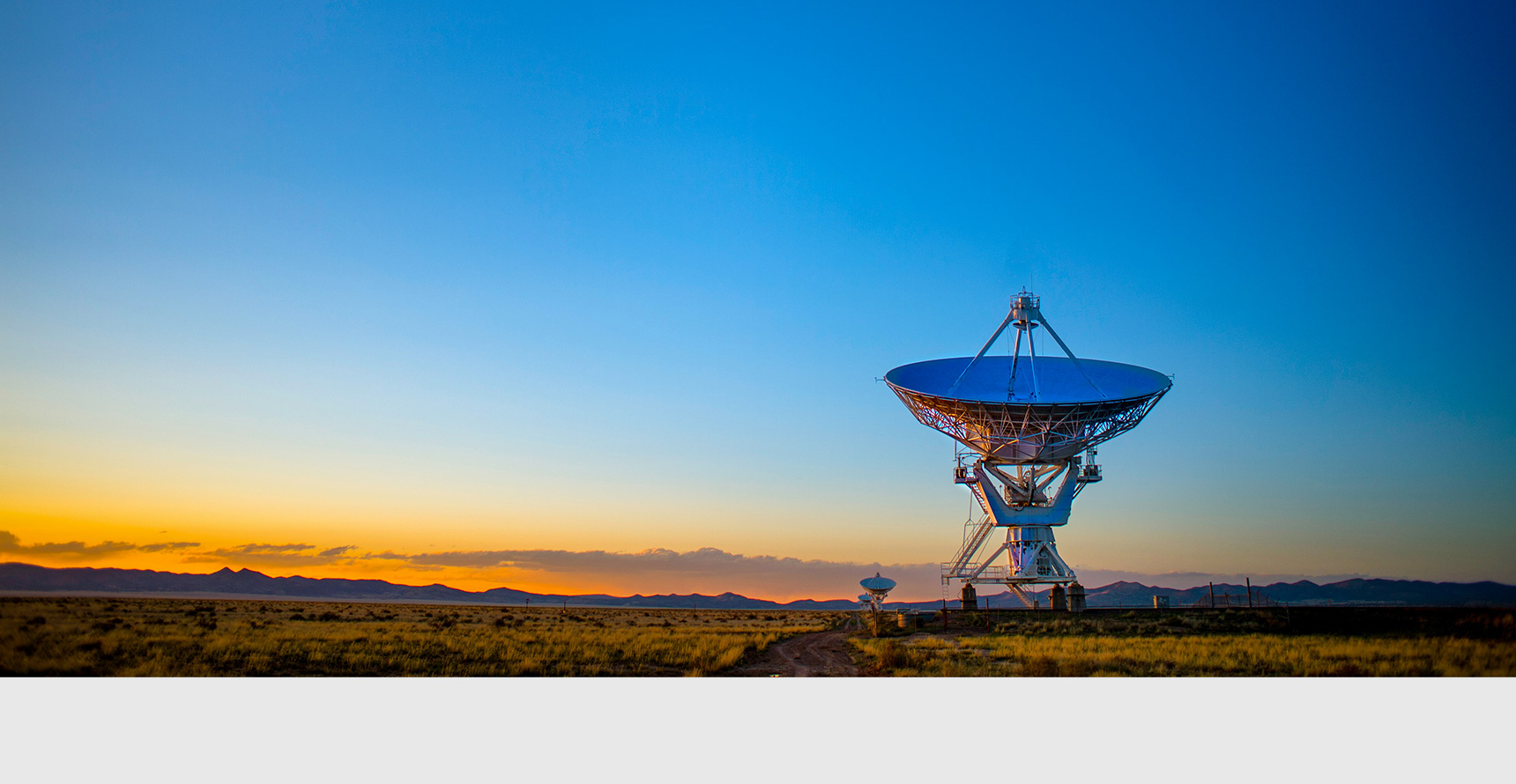 A satellite dish in a desert landscape at sunrise