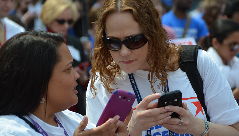 Two young voters look at their cell phones while being asked to text their Congressional representatives during the Rally for Medical Research in Washington, D.C.